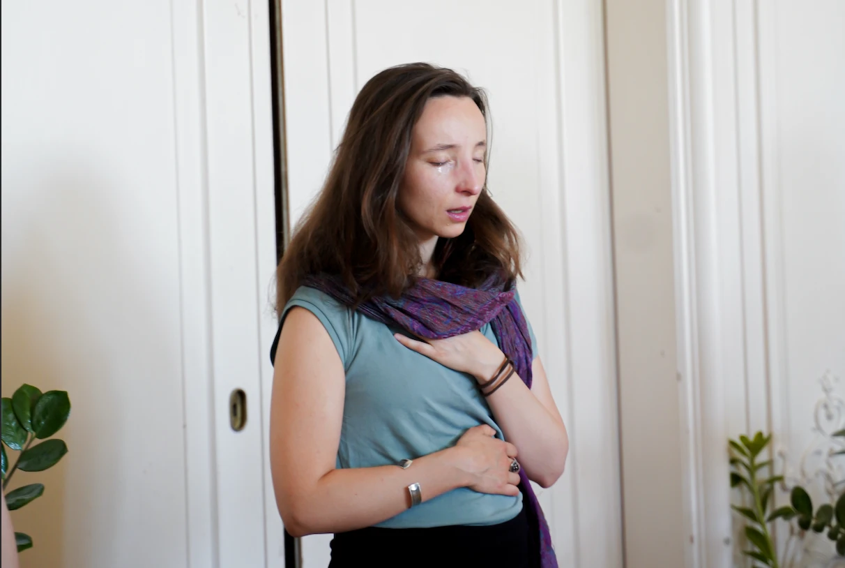 A woman pausing with one hand on her heart and one on her body